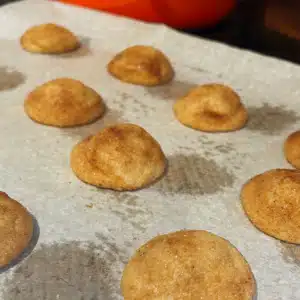 Baked snickerdoodle cookies resting on the sheet pan on parchment paper.
