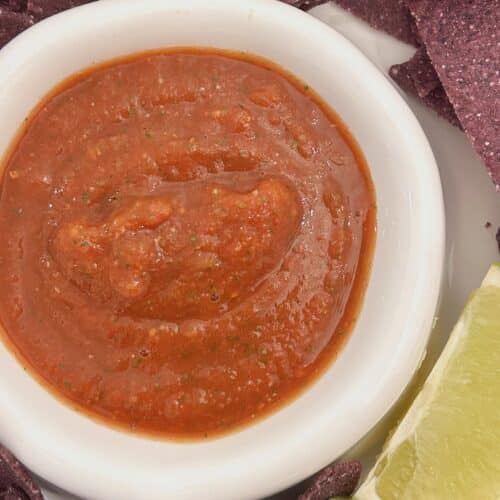 Easy Homemade Mexican Salsa served with tortilla chipis and lime wedges.