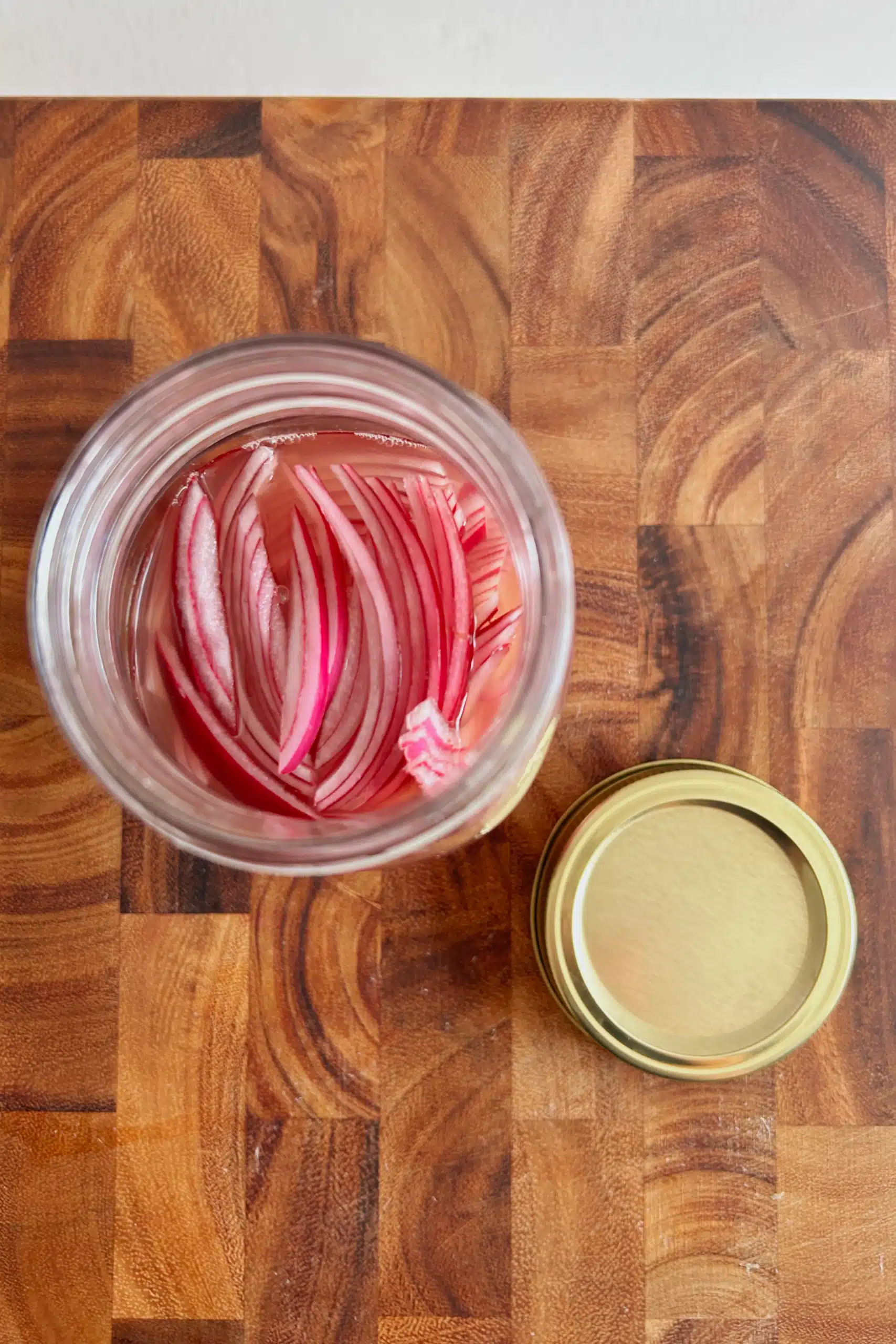Top view of thinly sliced pickled red onions in a mason jar.
