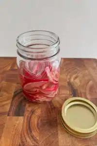Thinly sliced red onions and apple cider vinegar in a mason jar.